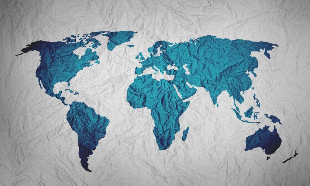 Um mapa-múndi exibido em um fundo enrugado e texturizado evoca a sensação de um papel amassado.
Os continentes, sombreados em azul, e os oceanos brancos criam um contraste impressionante.
Esse é o pano de fundo ideal para empresas que desejam contratar funcionários na América Latina sem uma presença local da empresa.  