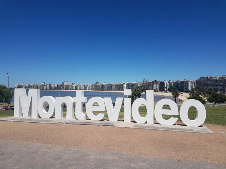 Grandes letras blancas deletrean "Montevideo" en un entorno de parque con edificios de la ciudad de fondo y un cielo azul y despejado, encarnando el vibrante espíritu de las startups uruguayas.