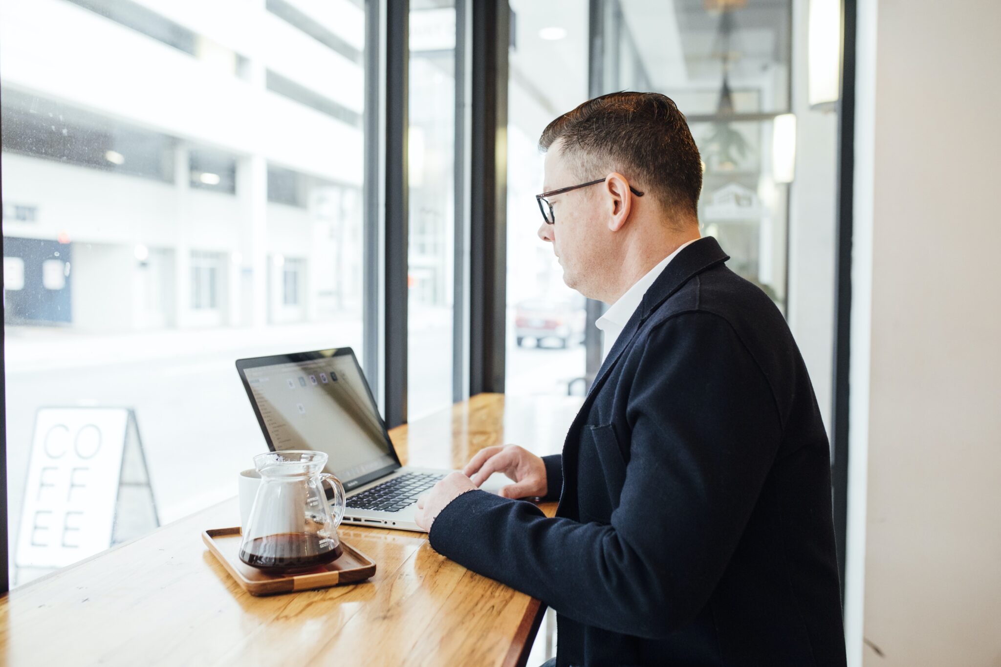 Homem de negócios em uma cafeteria em frente a um computador, representando um advogado corporativo na República Dominicana.