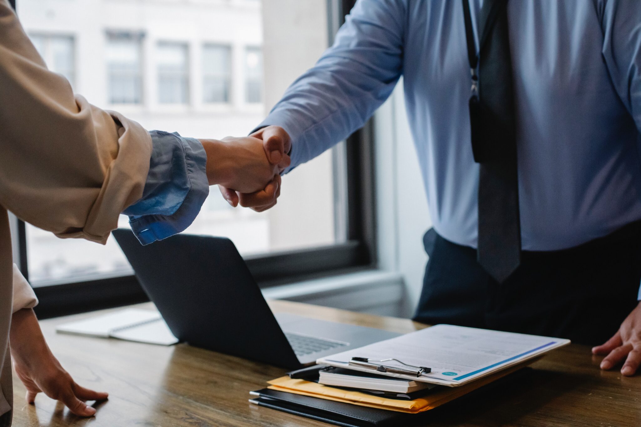 Duas pessoas apertando as mãos, representando um recrutador conversando com um candidato a emprego sobre seu histórico de trabalho como parte de um processo de verificação de antecedentes no Peru
