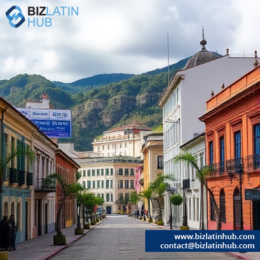 A picturesque street lined with colorful colonial-style buildings, leading towards lush green mountains. The sky is partly cloudy, and there are palm trees along the sidewalk. A sign on a building advertises "Biz Latin Hub" with their website and contact details.